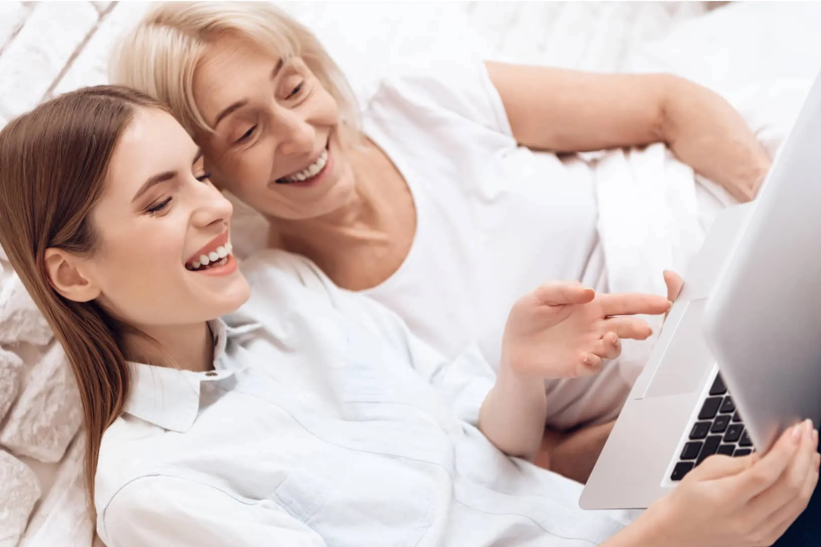 A care professional assisting an older woman at home with a computer